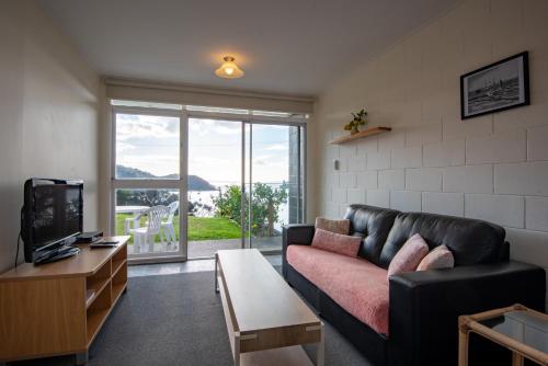 a living room with a couch and a tv at Mangonui Motel in Mangonui