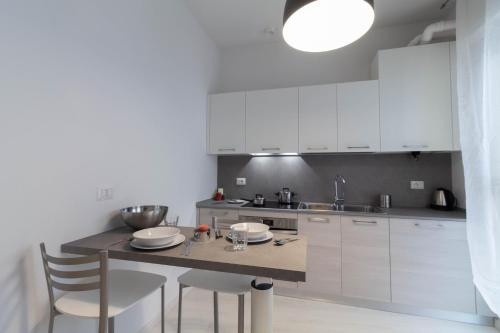 a kitchen with white cabinets and a table and chairs at Le Casette Di Osvaldo in Lecco