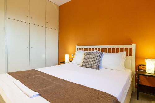 a bedroom with a white bed with an orange wall at Elaionas in Leonidio