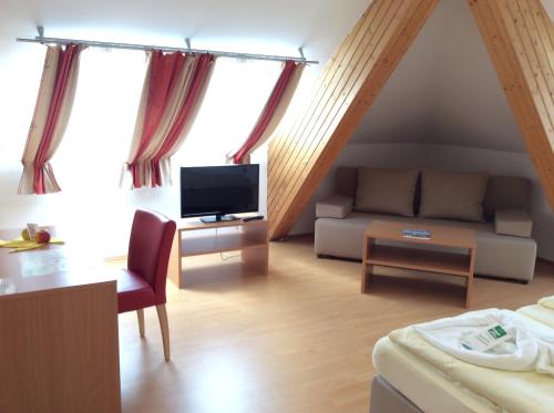a living room with a couch and a tv at Stadthotel Schwerterbräu in Judenburg