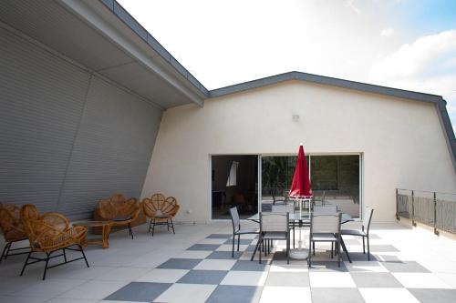 a patio with a table and chairs and a red umbrella at Champagne André Bergère - Guest House in Épernay