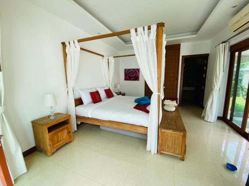 sypialnia z łóżkiem z baldachimem i czerwonymi poduszkami w obiekcie 3 Bedroom Villa SDV033-just 3 minutes walk to the beach-By Samui Dream Villas w mieście Mae Nam