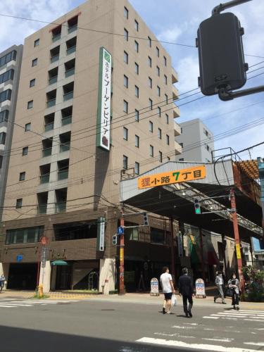 people crossing a street in front of a building at Hotel Bougain Villea Sapporo in Sapporo