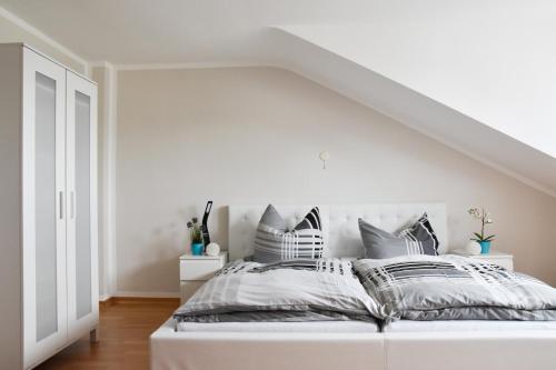 a white bedroom with a white bed with gray pillows at Mads Hotel in Cologne