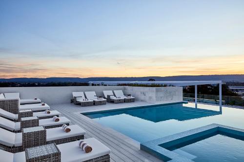 a swimming pool with lounge chairs on a roof at Astina Suites, Penrith in Penrith