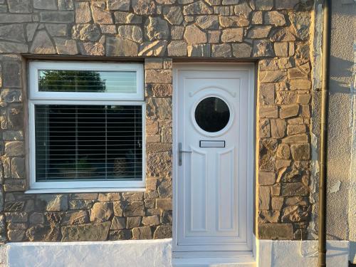 un edificio de piedra con una puerta blanca y una ventana en Westend Holiday Let 1 Brecon, en Brecon