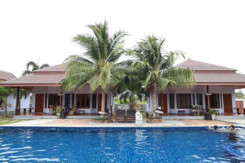 a villa with a swimming pool and palm trees at Waterside Resort in Pran Buri