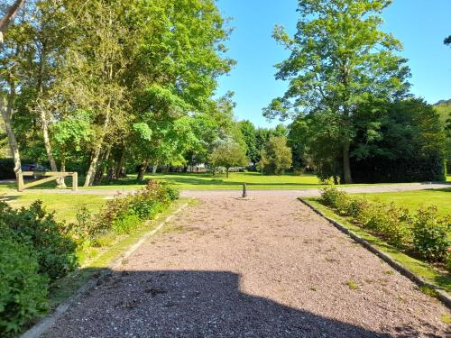 un chemin de gravier dans un parc arboré dans l'établissement Château des Bosquets, à Étretat
