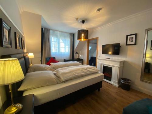 Schlafzimmer mit einem Bett, einem Kamin und einem TV in der Unterkunft Hotel Niedersachsen in Quakenbrück