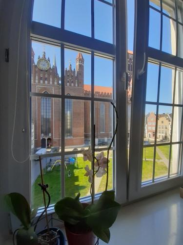 a window with a view of a building with a clock tower at Apartment in Old Town - view of Mariacki Church in Gdańsk