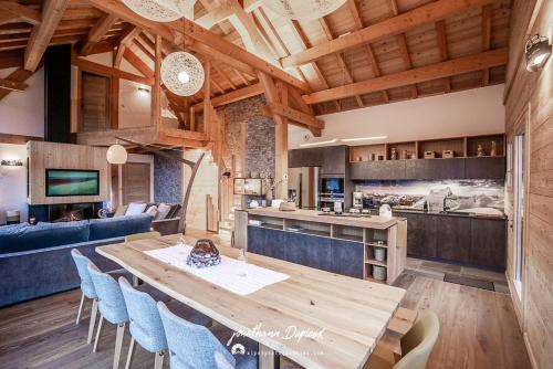 kuchnia i salon z drewnianym stołem i krzesłami w obiekcie Chalet Ecrin w mieście Saint-Chaffrey