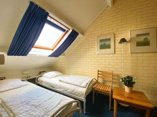 a room with two beds and a table and a window at Hello Zeeland - Vakantiehuis Duinroos 181 in Breskens