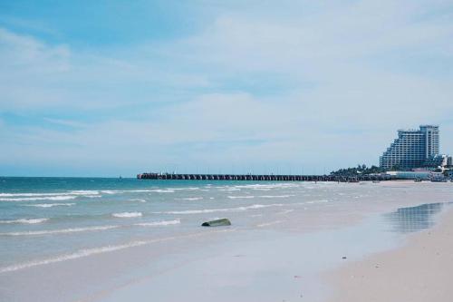 a sandy beach with a pier in the ocean at Green Gallery Beach Boutique Hotel in Hua Hin