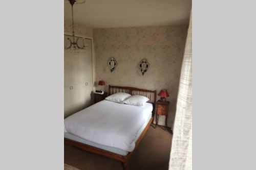 Schlafzimmer mit einem Bett mit weißer Bettwäsche und Blumentapete in der Unterkunft Appartement spacieux 78m2 plein centre, balcon, jusqu’à 6 personnes in La Bourboule