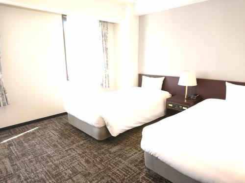 札幌市にあるホテルブーゲンビリア札幌のベッド2台と窓が備わるホテルルームです。