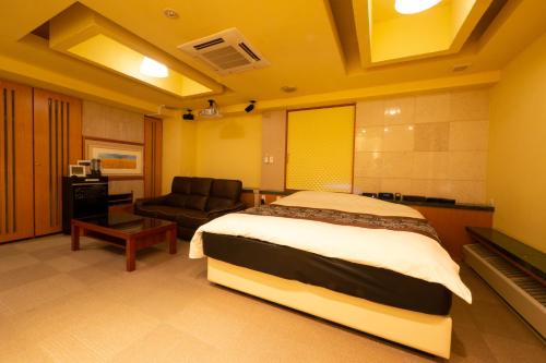 a hotel room with a bed and a chair at HOTEL Rplus日高 in Hidaka