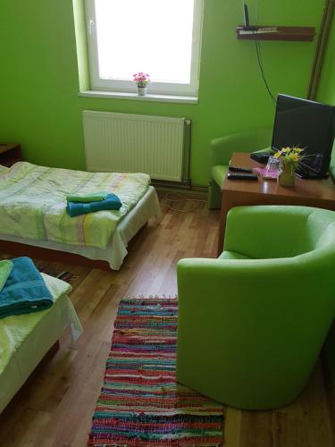 a green room with a bed and a chair and a desk at FAN FAN PENZIÓN in Rožňava