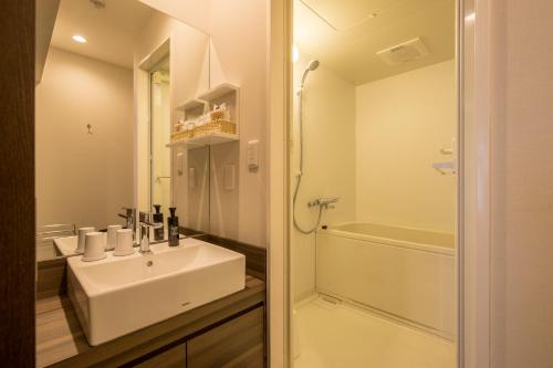 a white bathroom with a sink and a shower at HOTEL R9 Kujukuri "ex Casual Resort COFF Ichinomiya" in Ichinomiya