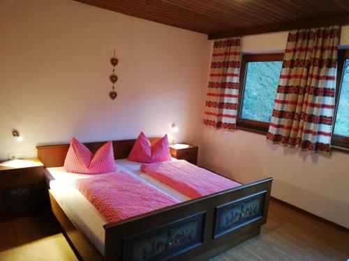 a bedroom with a large bed with pink pillows at Landhaus Kohlstatt in Finkenberg