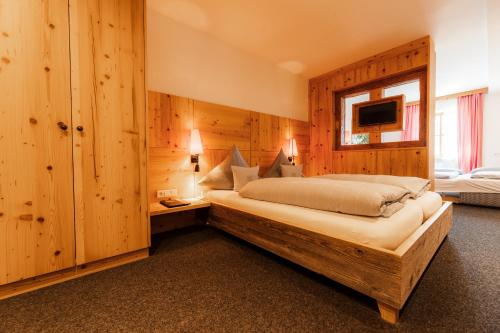 een slaapkamer met een groot bed in een kamer met houten wanden bij Gasthof Bogenrieder in Pörnbach