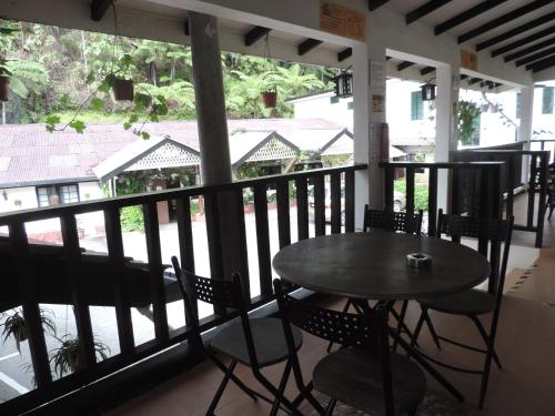 a table and chairs on a porch with a view of the street at Cameronian Inn in Cameron Highlands