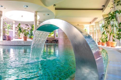a pool with a water fountain in a building at Residence Hotel Balaton in Siófok