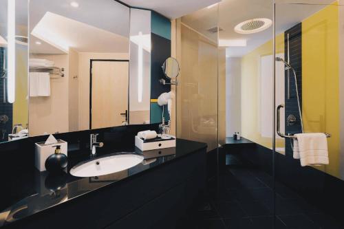 a bathroom with a sink and a glass shower at The Kuala Lumpur Journal Hotel in Kuala Lumpur