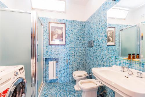 a blue tiled bathroom with a toilet and a sink at Milan Retreats in Milan