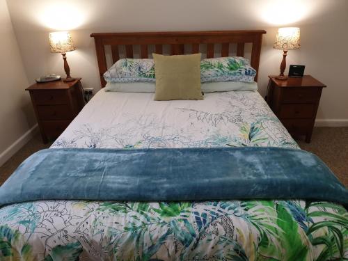 a bed with a blue comforter and two night stands at River House Mudgee in Mudgee