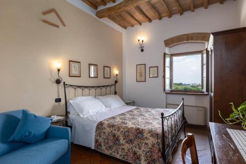 サン・ジミニャーノにあるアグリツーリズモ イル カゾラーレ ディ ブッチャーノのベッドルーム1室(ベッド1台、ソファ、窓付)