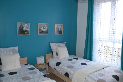 a bedroom with two beds and a blue wall at ESCALE À ÉPERNAY BORDS DE MARNE APPT 2/4 PERS in Épernay
