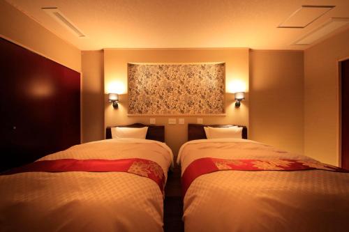 two beds in a room with a painting on the wall at Tensui Saryo in Hakone