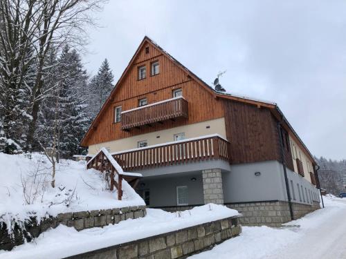 a large wooden building with snow on the ground at Apartmán Janina in Janov nad Nisou