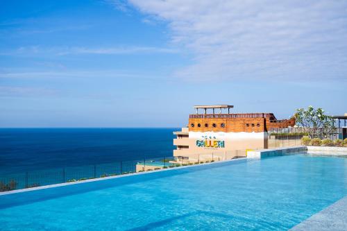 a swimming pool on top of a building with the ocean at The Sea Galleri by Katathani - SHA Plus in Kata Beach