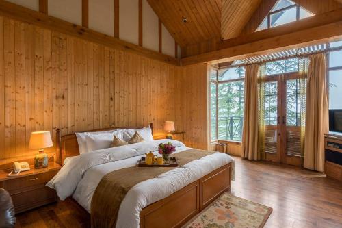 a bedroom with a large bed in a room with wooden walls at StayVista at Wood House Retreat in Shimla