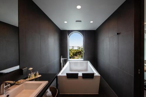 a bathroom with a tub and a sink and a window at AG405 Hotel in Busan