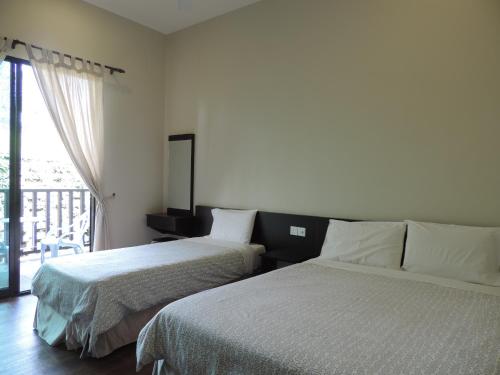 a bedroom with two beds and a window with a balcony at Cameronian Inn in Cameron Highlands
