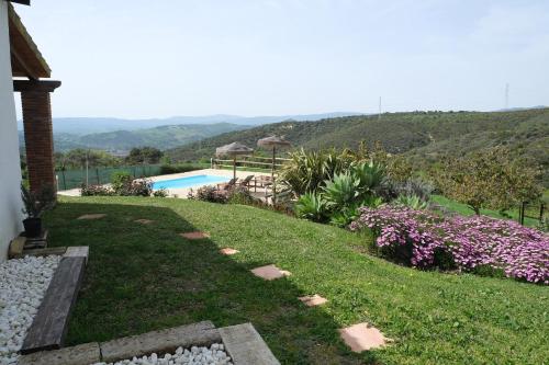 a backyard with a swimming pool and a garden with flowers at The Wild Olive Andalucía Palma Guestroom in Casares