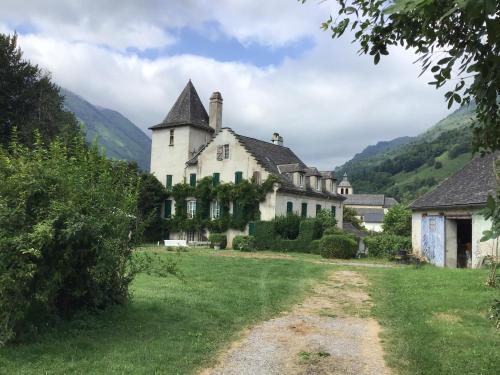 an old house in a field with mountains in the background at Maison Laclede in Bedous