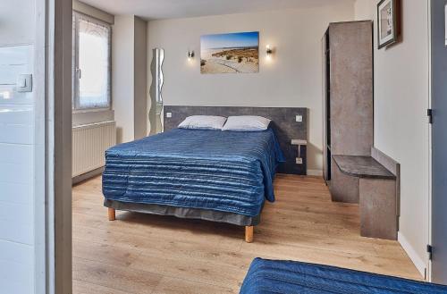a bedroom with a bed with a blue blanket at Hotel Restaurant L'Atlantique in Saint-Jean-de-Monts