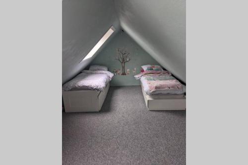 a attic bedroom with two beds and a tree on the wall at Glendyne Cottages, Highest Village in Scotland in Wanlockhead