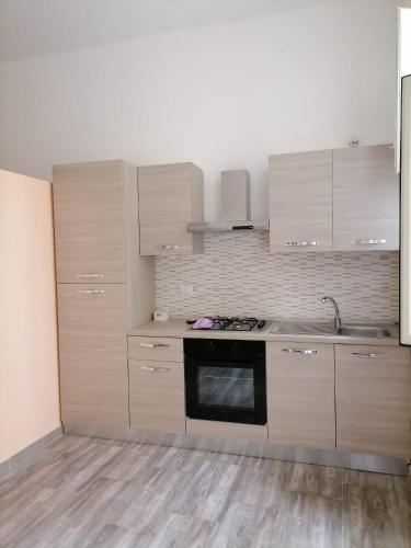una cocina con armarios blancos y horno negro en la casetta, en Termini Imerese