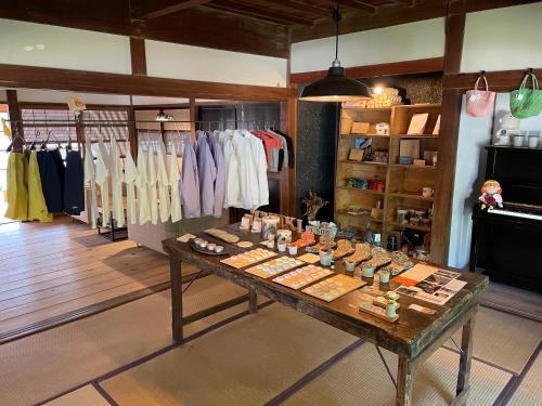 MEKIKI古民家 في ياماناشي: يوجد متجر للملابس مع طاولة عليها ملابس.