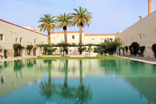 a pool of water with palm trees in front of a building at Convento Bernardas duplex BL - 3 bedroom in Tavira