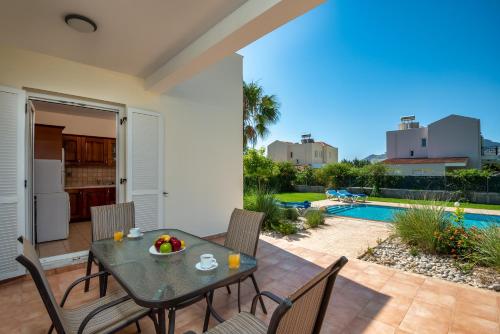 a patio with a table and chairs and a pool at Athena Villa in Kolimbia