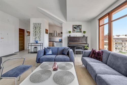 a living room with two blue couches and a table at Grand Apartments - Neptun Park. in Gdańsk