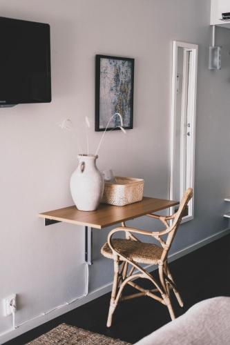 a table with a vase on top of it with a chair at Skärgårdshotellet Hönö in Hönö