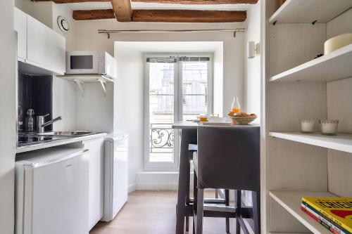 une cuisine avec des placards blancs et un comptoir avec une table dans l'établissement New Cocoon Duplex for 2 in the Heart of Paris (5D), à Paris