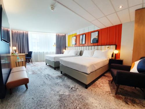 a hotel room with two beds and a couch at voco Dusseldorf Seestern, an IHG Hotel in Düsseldorf