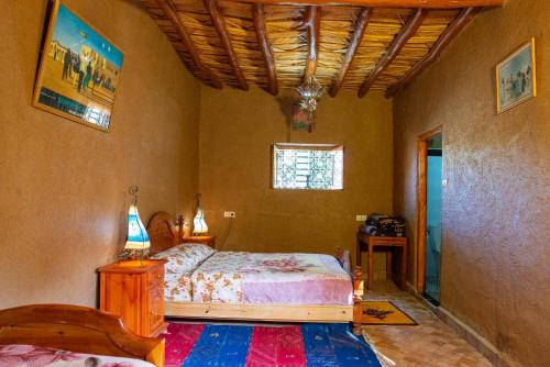 Schlafzimmer mit einem Bett, einem Tisch und einem Fenster in der Unterkunft Maison Nomades in Aït Boukha